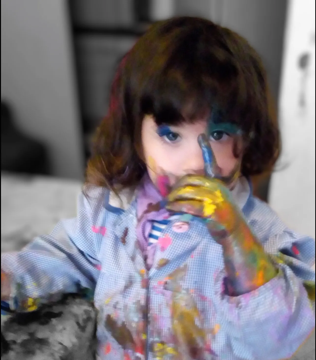Niña con la cara pintada de colores sosteniendo un frasco de témpera